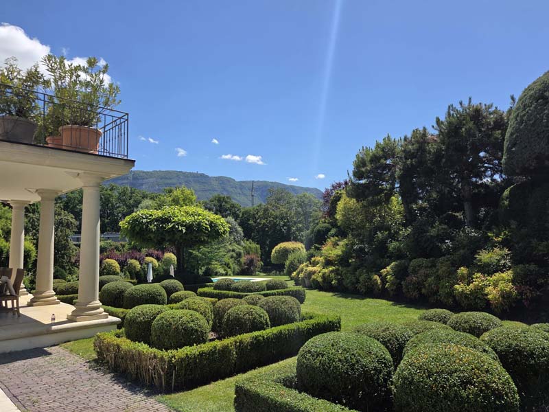 Jardin paysager avec haies taillées, massifs fleuris et pelouse entretenue en Suisse romande
